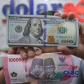 Petugas menjunjukkan uang pecahan dolar Amerika Serikat (AS) dan rupiah di Dolar Asia Money Changer, Jakarta, Rabu (8/7/2026). (CNBC Indonesia/Faisal Rahman)