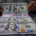Petugas menjunjukkan uang pecahan dolar Amerika Serikat (AS) dan rupiah diDolar Asia Money Changer, Jakarta, Rabu (8/7/2026).(CNBC Indonesia/Faisal Rahman)