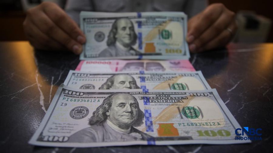 Petugas menjunjukkan uang pecahan dolar Amerika Serikat (AS) dan rupiah diDolar Asia Money Changer, Jakarta, Rabu (8/7/2026).(CNBC Indonesia/Faisal Rahman)