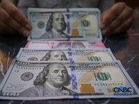 Petugas menjunjukkan uang pecahan dolar Amerika Serikat (AS) dan rupiah diDolar Asia Money Changer, Jakarta, Rabu (8/7/2026).(CNBC Indonesia/Faisal Rahman)
