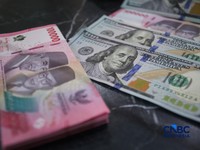 Petugas menjunjukkan uang pecahan dolar Amerika Serikat (AS) dan rupiah di Dolar Asia Money Changer, Jakarta, Rabu (8/7/2026). (CNBC Indonesia/Faisal Rahman)