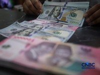 Petugas menjunjukkan uang pecahan dolar Amerika Serikat (AS) dan rupiah di Dolar Asia Money Changer, Jakarta, Rabu (8/7/2026). (CNBC Indonesia/Faisal Rahman)