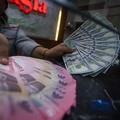 Petugas menjunjukkan uang pecahan dolar Amerika Serikat (AS) dan rupiah di Dolar Asia Money Changer, Jakarta, Rabu (8/7/2026). (CNBC Indonesia/Faisal Rahman)