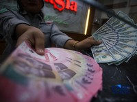 Petugas menjunjukkan uang pecahan dolar Amerika Serikat (AS) dan rupiah di Dolar Asia Money Changer, Jakarta, Rabu (8/7/2026). (CNBC Indonesia/Faisal Rahman)