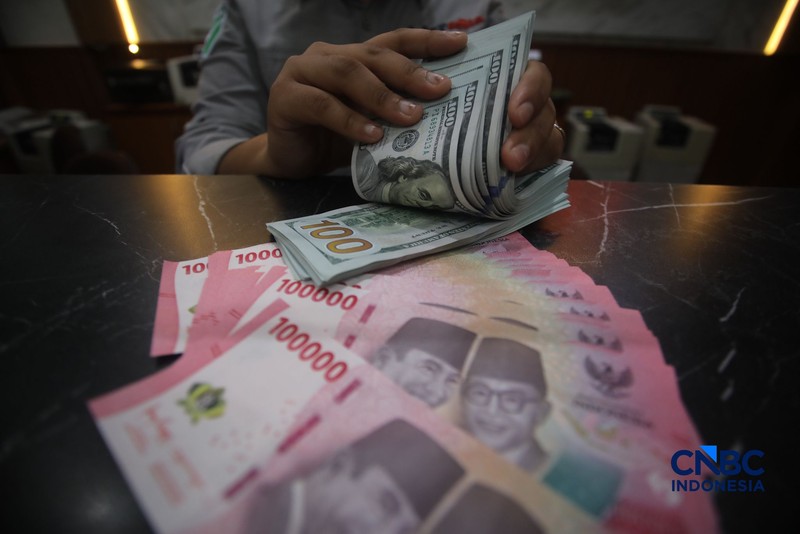 Petugas menjunjukkan uang pecahan dolar Amerika Serikat (AS) dan rupiah di Dolar Asia Money Changer, Jakarta, Rabu (8/7/2026). (CNBC Indonesia/Faisal Rahman)