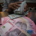 Petugas menjunjukkan uang pecahan dolar Amerika Serikat (AS) dan rupiah di Dolar Asia Money Changer, Jakarta, Rabu (8/7/2026). (CNBC Indonesia/Faisal Rahman)