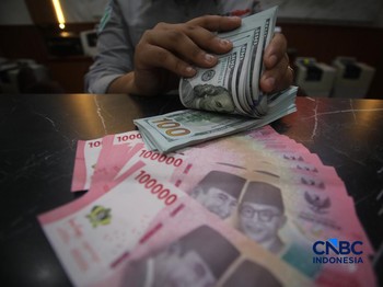Petugas menjunjukkan uang pecahan dolar Amerika Serikat (AS) dan rupiah diDolar Asia Money Changer, Jakarta, Rabu (8/7/2026).(CNBC Indonesia/Faisal Rahman)