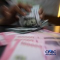 Petugas menjunjukkan uang pecahan dolar Amerika Serikat (AS) dan rupiah di Dolar Asia Money Changer, Jakarta, Rabu (8/7/2026). (CNBC Indonesia/Faisal Rahman)