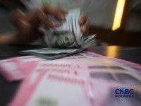 Petugas menjunjukkan uang pecahan dolar Amerika Serikat (AS) dan rupiah di Dolar Asia Money Changer, Jakarta, Rabu (8/7/2026). (CNBC Indonesia/Faisal Rahman)