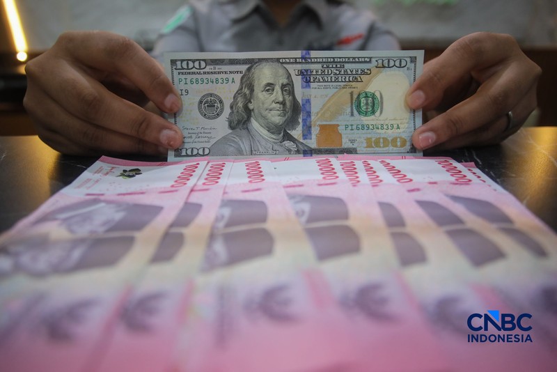 Petugas menjunjukkan uang pecahan dolar Amerika Serikat (AS) dan rupiah di Dolar Asia Money Changer, Jakarta, Rabu (8/7/2026). (CNBC Indonesia/Faisal Rahman)