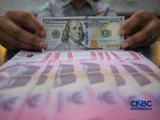 Petugas menjunjukkan uang pecahan dolar Amerika Serikat (AS) dan rupiah di Dolar Asia Money Changer, Jakarta, Rabu (8/7/2026). (CNBC Indonesia/Faisal Rahman)