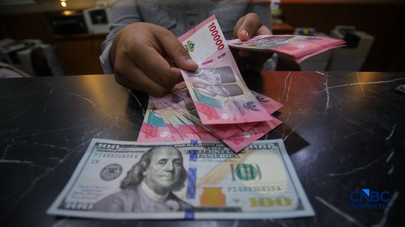 Petugas menjunjukkan uang pecahan dolar Amerika Serikat (AS) dan rupiah di Dolar Asia Money Changer, Jakarta, Rabu (8/7/2026). (CNBC Indonesia/Faisal Rahman)
