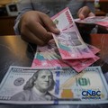 Petugas menjunjukkan uang pecahan dolar Amerika Serikat (AS) dan rupiah di Dolar Asia Money Changer, Jakarta, Rabu (8/7/2026). (CNBC Indonesia/Faisal Rahman)