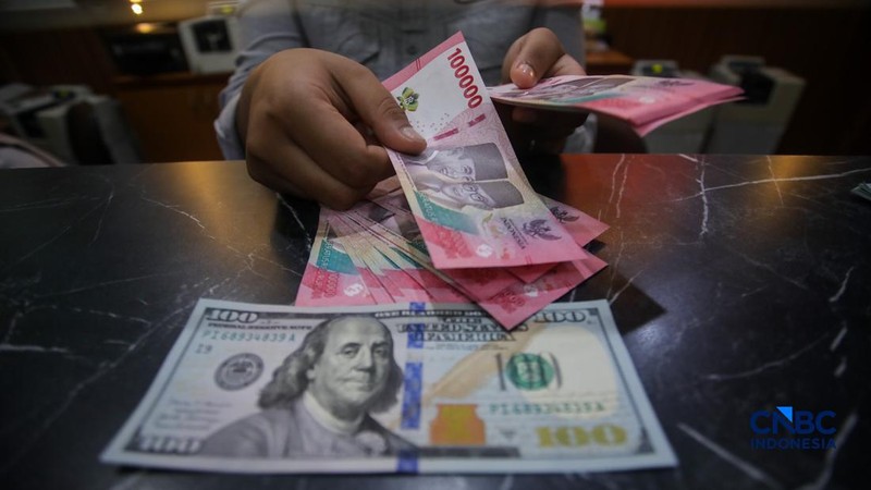 Petugas menjunjukkan uang pecahan dolar Amerika Serikat (AS) dan rupiah di Dolar Asia Money Changer, Jakarta, Rabu (8/7/2026).