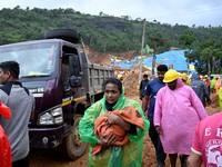 Seorang wanita menggendong bayi saat ia berpindah ke tempat yang lebih aman setelah tanah longsor di dekat Jembatan Meenakshi, dekat lokasi proyek terowongan di distrik Wayanad, di negara bagian Kerala selatan, India, 7 Juli 2026. (REUTERS/CK Thansee
