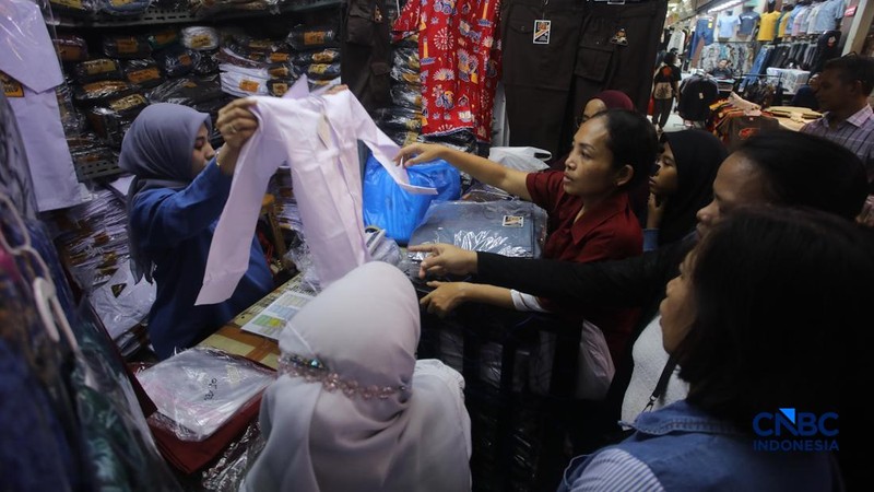 Orang tua mencocokkan seragam sekolah ke anaknya pada toko penyedia seragam sekolah di Pasar Tanah Abang, Jakarta, Kamis (9/7/2026).