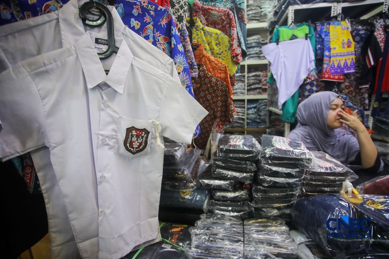 Orang tua mencocokkan seragam sekolah ke anaknya pada toko penyedia seragam sekolah di Pasar Tanah Abang, Jakarta, Kamis (9/7/2026). (CNBC Indonesia/Faisal Rahman)