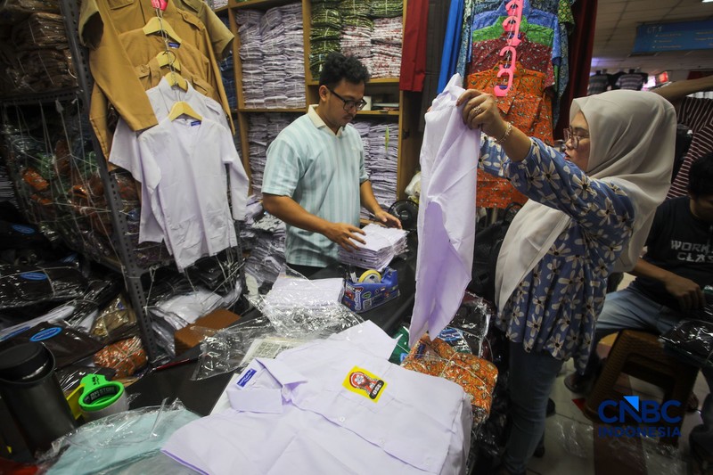 Orang tua mencocokkan seragam sekolah ke anaknya pada toko penyedia seragam sekolah di Pasar Tanah Abang, Jakarta, Kamis (9/7/2026). (CNBC Indonesia/Faisal Rahman)