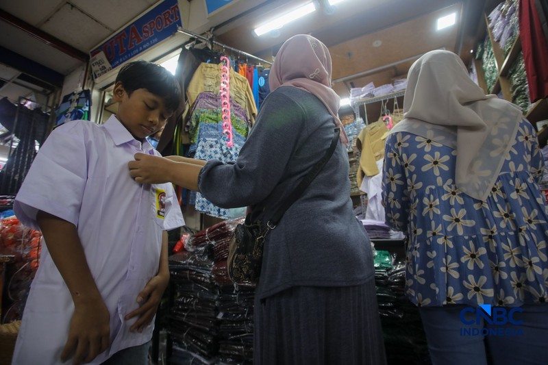 Orang tua mencocokkan seragam sekolah ke anaknya pada toko penyedia seragam sekolah di Pasar Tanah Abang, Jakarta, Kamis (9/7/2026). (CNBC Indonesia/Faisal Rahman)