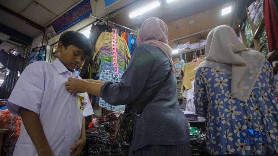Orang tua mencocokkan seragam sekolah ke anaknya pada toko penyedia seragam sekolah di Pasar Tanah Abang, Jakarta, Kamis (9/7/2026). (CNBC Indonesia/Faisal Rahman)