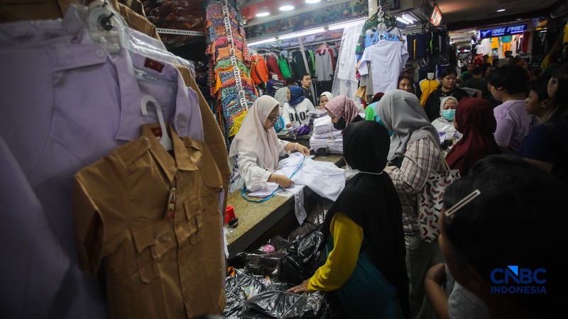Orang tua mencocokkan seragam sekolah ke anaknya pada toko penyedia seragam sekolah di Pasar Tanah Abang, Jakarta, Kamis (9/7/2026). (CNBC Indonesia/Faisal Rahman)