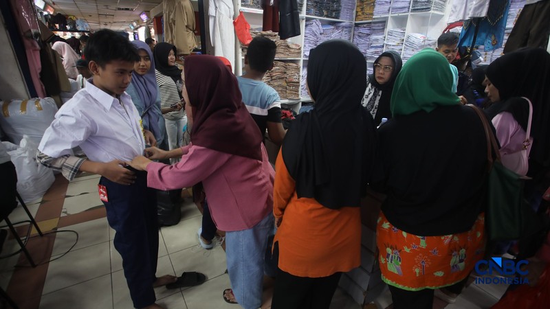 Orang tua mencocokkan seragam sekolah ke anaknya pada toko penyedia seragam sekolah di Pasar Tanah Abang, Jakarta, Kamis (9/7/2026). (CNBC Indonesia/Faisal Rahman)