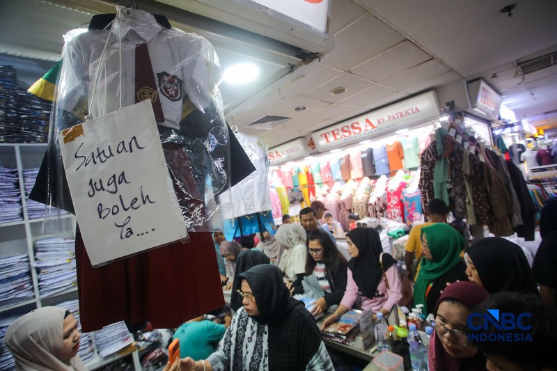 Orang tua mencocokkan seragam sekolah ke anaknya pada toko penyedia seragam sekolah di Pasar Tanah Abang, Jakarta, Kamis (9/7/2026). (CNBC Indonesia/Faisal Rahman)