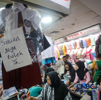 Orang tua mencocokkan seragam sekolah ke anaknya pada toko penyedia seragam sekolah di Pasar Tanah Abang, Jakarta, Kamis (9/7/2026). (CNBC Indonesia/Faisal Rahman)