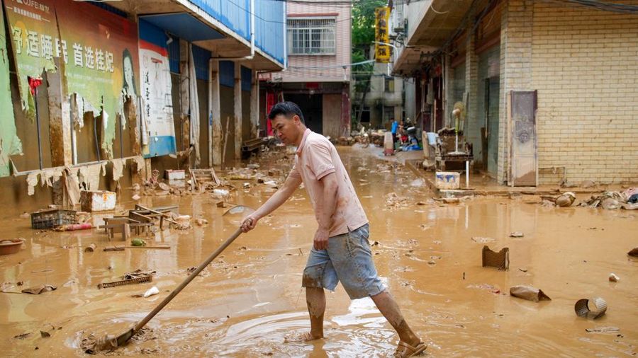 Seorang pria membersihkan lumpur setelah hujan lebat yang dibawa oleh topan Maysak di kota Sanli yang terendam banjir di Guigang, Daerah Otonomi Guangxi Zhuang, Tiongkok, 9 Juli 2026.