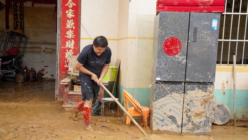 Seorang warga membersihkan lumpur dari rumah yang terendam banjir setelah hujan lebat akibat topan Maysak, dekat Waduk Liulan di Hengzhou, Daerah Otonomi Guangxi Zhuang, Tiongkok, 8 Juli 2026.