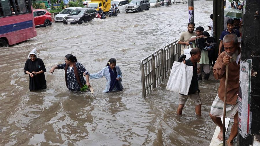 Orang-orang dan kendaraan bergerak melintasi jalan yang tergenang banjir setelah hujan deras di Dhaka, Bangladesh, 12 Juli 2026.