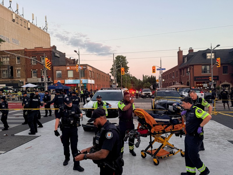 Orang-orang berkumpul saat petugas darurat memberikan pertolongan di lokasi kejadian setelah penembakan mematikan, di sebuah festival jalanan bertema salsa di Toronto, Ontario, Kanada, 11 Juli 2026. (REUTERS/Cole Burston)