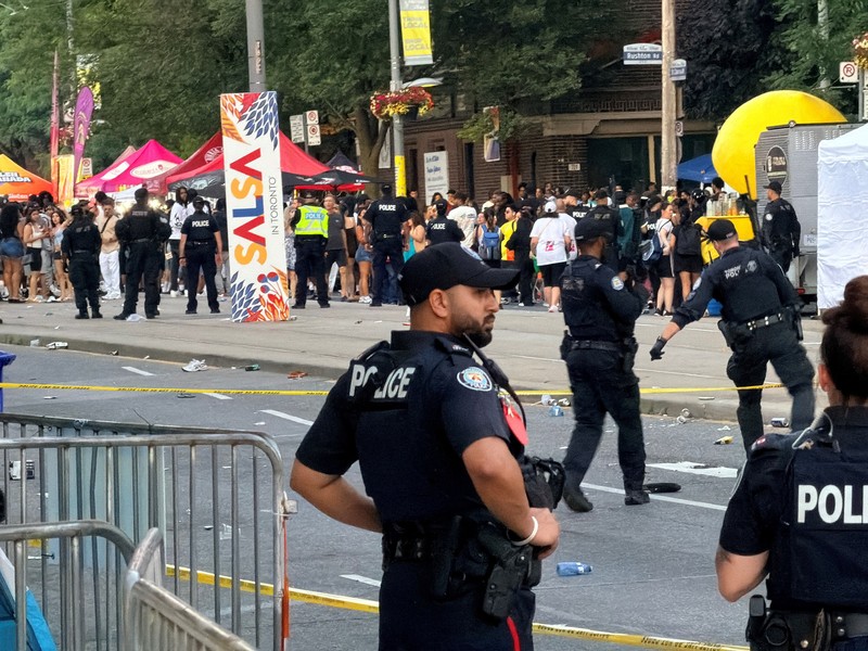 Orang-orang berkumpul saat petugas darurat memberikan pertolongan di lokasi kejadian setelah penembakan mematikan, di sebuah festival jalanan bertema salsa di Toronto, Ontario, Kanada, 11 Juli 2026. (REUTERS/Cole Burston)