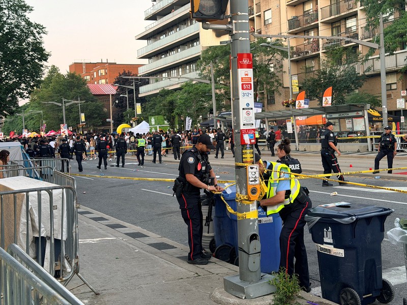Orang-orang berkumpul saat petugas darurat memberikan pertolongan di lokasi kejadian setelah penembakan mematikan, di sebuah festival jalanan bertema salsa di Toronto, Ontario, Kanada, 11 Juli 2026. (REUTERS/Cole Burston)