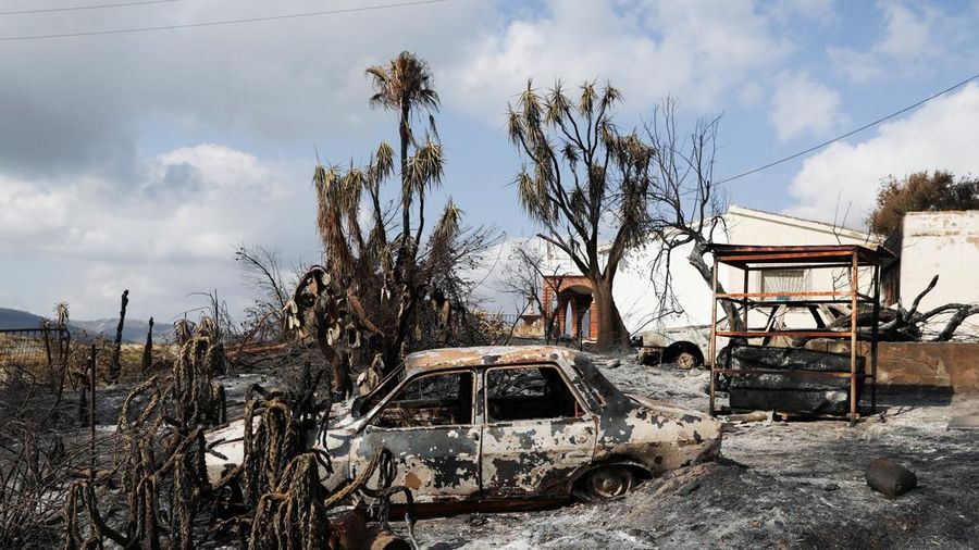 Sebuah mobil hangus di depan rumah yang rusak di daerah yang terbakar akibat kebakaran hutan mematikan di Almocaizar, Almeria, Spanyol, 12 Juli 2026.