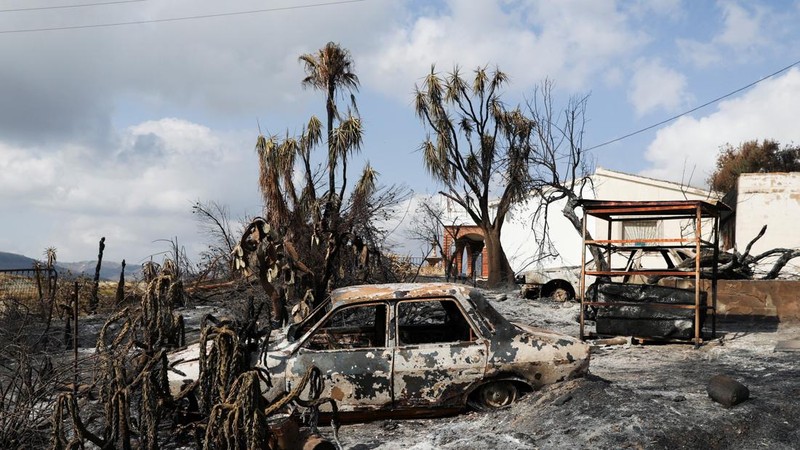 Sebuah mobil hangus di depan rumah yang rusak di daerah yang terbakar akibat kebakaran hutan mematikan di Almocaizar, Almeria, Spanyol, 12 Juli 2026.