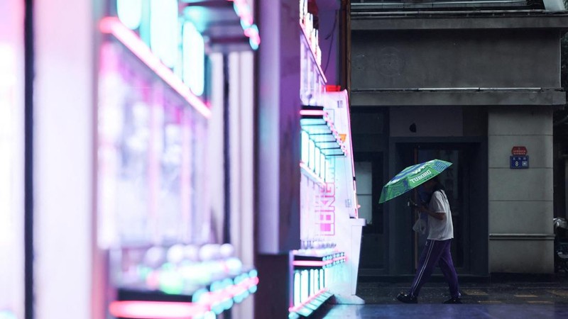 Seseorang berjalan sambil membawa payung saat hujan semakin deras menjelang kedatangan Topan Bavi di Wenzhou, provinsi Zhejiang, Tiongkok, 11 Juli 2026. (REUTERS/Go Nakamura)