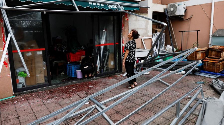 Ye Qiuyan, pemilik sebuah toko, melihat tenda yang rusak akibat Topan Bavi di desa pesisir Diaocaocun, Taizhou, provinsi Zhejiang, Tiongkok, 12 Juli 2026.