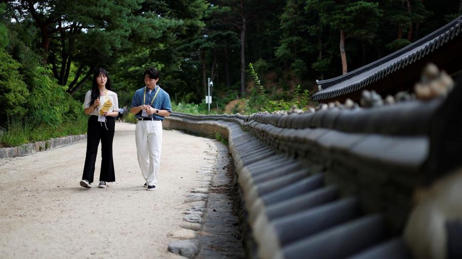 Dua peserta berbincang sambil berjalan selama program perjodohan di kuil Buddha untuk pria dan wanita lajang di kuil Naksansa di Yangyang, Korea Selatan, 11 Juli 2026.