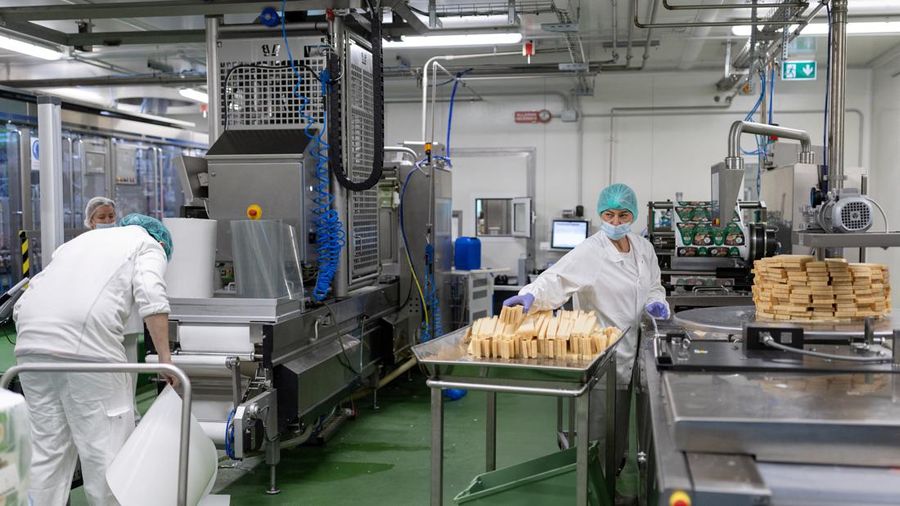 Para pekerja memotong dan menumpuk stik keju Parmigiano Reggiano di jalur pengemasan di Caseifici GranTerre, yang menyatakan bahwa tagihan listrik telah meningkat karena gelombang panas yang lebih lama memaksa lebih banyak pendinginan di dalam pabrik, di Montecavolo di Quattro Castella, Italia, 6 Juli 2026.