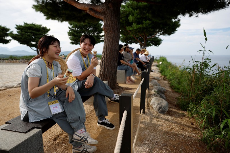 Para peserta berjalan di sekitar halaman kuil Naksansa selama program perjodohan kuil Buddha untuk pria dan wanita lajang di Yangyang, Korea Selatan, 11 Juli 2026. (REUTERS/Kim Soo-hyeon)