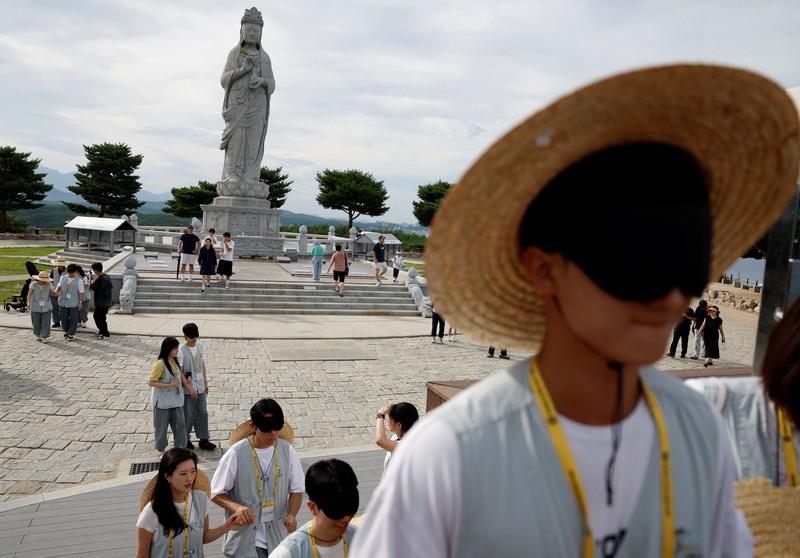 Para peserta berjalan di sekitar halaman kuil Naksansa selama program perjodohan kuil Buddha untuk pria dan wanita lajang di Yangyang, Korea Selatan, 11 Juli 2026. (REUTERS/Kim Soo-hyeon)