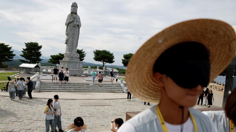 Para peserta yang matanya ditutup mengikuti kegiatan berjalan kaki yang dipandu di dekat patung Buddha selama program perjodohan di kuil Naksansa di Yangyang, Korea Selatan, 11 Juli 2026.