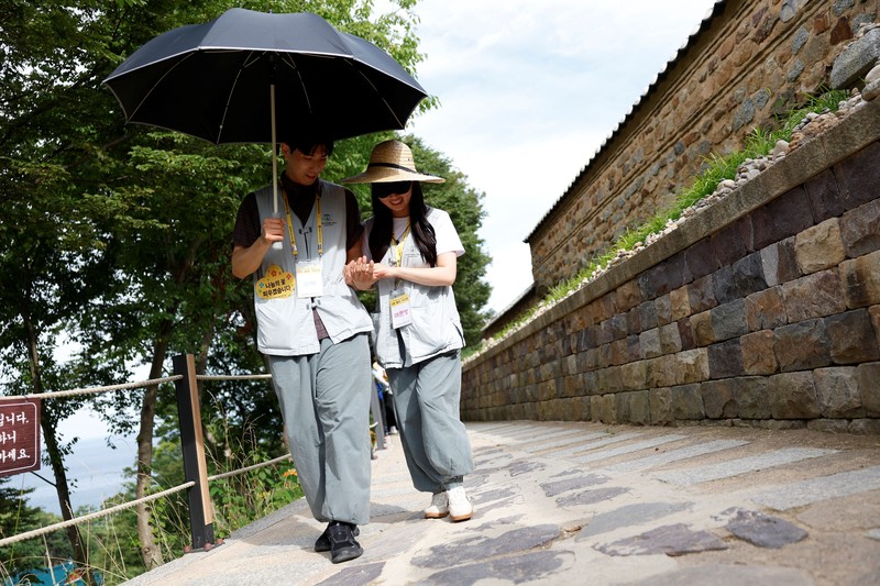 Para peserta berjalan di sekitar halaman kuil Naksansa selama program perjodohan kuil Buddha untuk pria dan wanita lajang di Yangyang, Korea Selatan, 11 Juli 2026. (REUTERS/Kim Soo-hyeon)