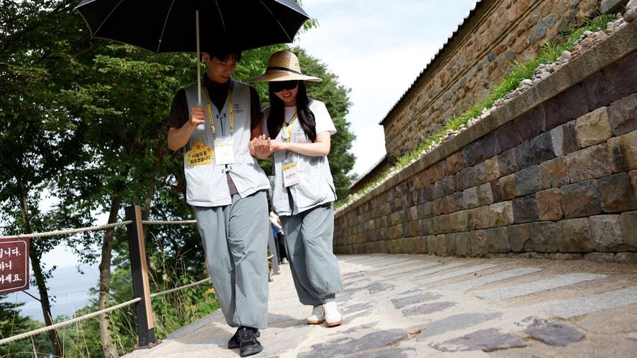Seorang peserta memandu pasangannya yang matanya ditutup di sepanjang jalan batu selama program perjodohan kuil Buddha di kuil Naksansa di Yangyang, Korea Selatan, 11 Juli 2026.