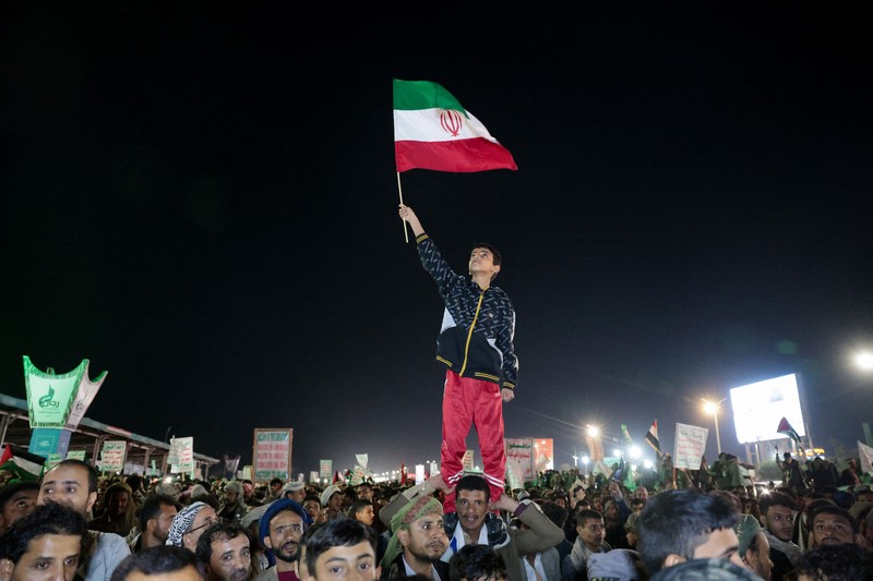 Seorang anak laki-laki melambaikan bendera Iran saat bergabung dengan pendukung Houthi dalam demonstrasi menentang serangan udara di Bandara Internasional Sanaa, di Sanaa, Yaman, 13 Juli 2026. (REUTERS/Khaled Abdullah)