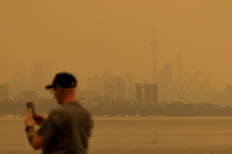 Seseorang menunjuk ke cakrawala saat menaiki feri dari Pulau Toronto, sementara asap kebakaran hutan dari Ontario barat laut memenuhi langit, ditambah dengan gelombang panas yang hebat, memicu peringatan kesehatan dan seruan kepada warga untuk membatasi aktivitas di luar ruangan di Toronto, Ontario, Kanada, 15 Juli 2026. (REUTERS/Carlos Osorio)