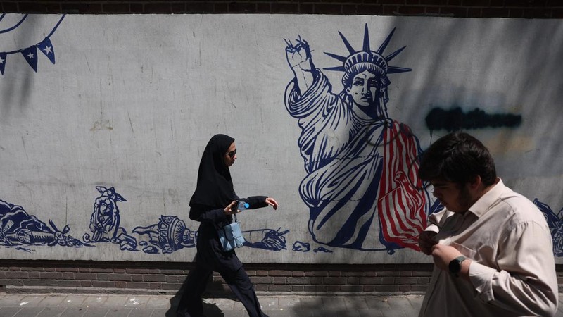 Orang-orang berjalan di dekat mural anti-AS di Teheran, Iran, 15 Juli 2026. (via REUTERS/Majid Asgaripour)