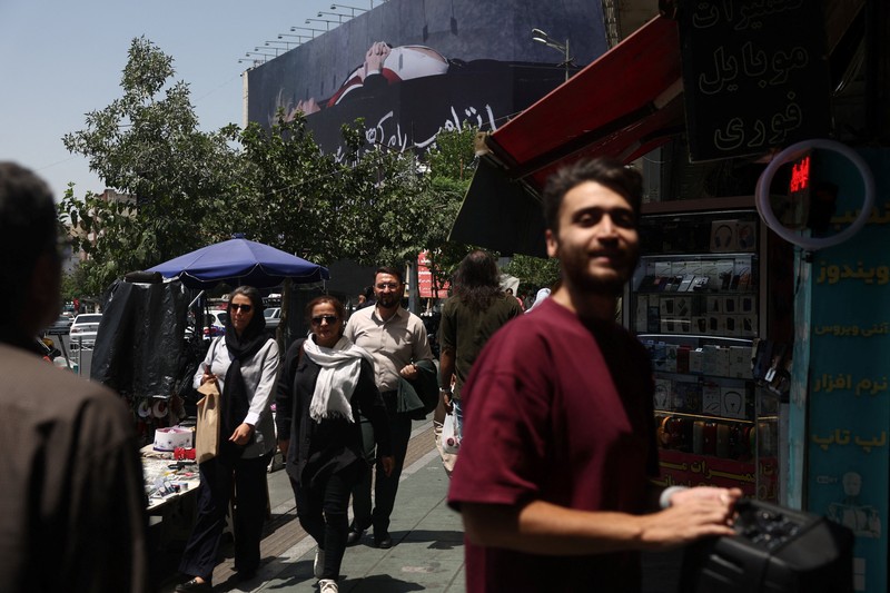 Papan reklame raksasa yang menampilkan ilustrasi Presiden AS Donald Trump berada di dalam peti mati yang terpampang di pusat kota Teheran, Kamis (16/7/2026). (via REUTERS/Majid Asgaripour)