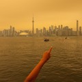 Seseorang menunjuk ke cakrawala saat menaiki feri dari Pulau Toronto, sementara asap kebakaran hutan dari Ontario barat laut memenuhi langit, ditambah dengan gelombang panas yang hebat, memicu peringatan kesehatan dan seruan kepada warga untuk membat